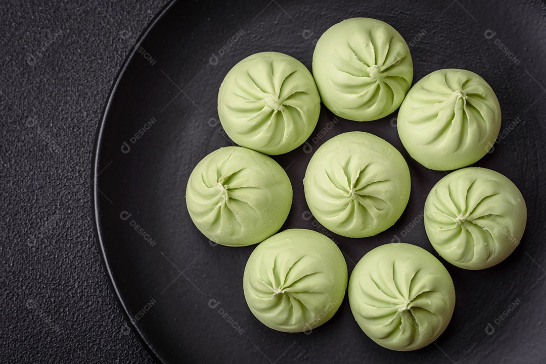 Khinkali cru ou bolinhos verdes com sal, especiarias e ervas sobre um fundo escuro de concreto