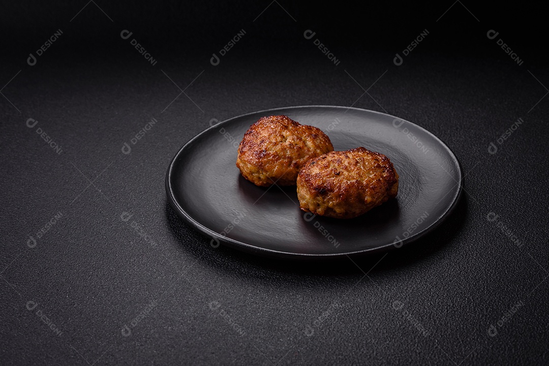 Deliciosas costeletas de peixe picado frito fresco com especiarias e ervas sobre um fundo escuro de concreto