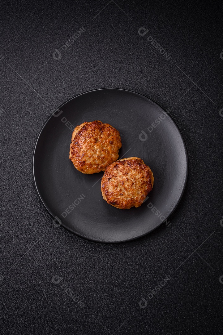 Deliciosas costeletas de peixe picado frito fresco com especiarias e ervas sobre um fundo escuro de concreto