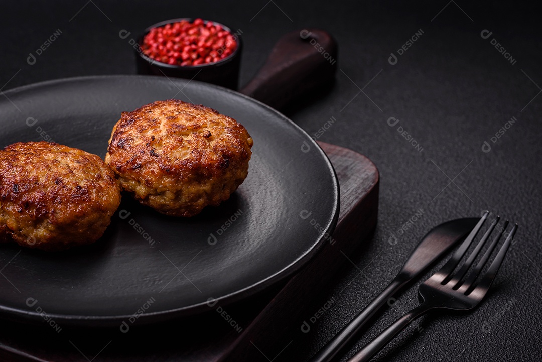 Deliciosas costeletas de peixe picado frito fresco com especiarias e ervas sobre um fundo escuro de concreto