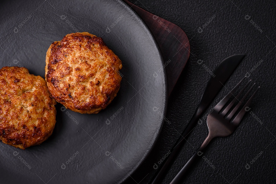 Deliciosas costeletas de peixe picado frito fresco com especiarias e ervas sobre um fundo escuro de concreto