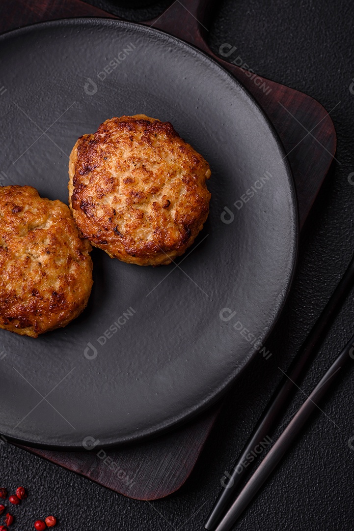 Deliciosas costeletas de peixe picado frito fresco com especiarias e ervas sobre um fundo escuro de concreto