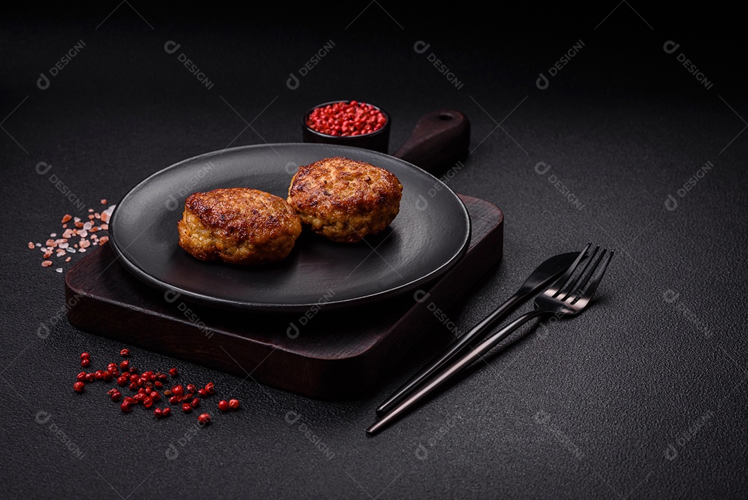 Deliciosas costeletas de peixe picado frito fresco com especiarias e ervas sobre um fundo escuro de concreto