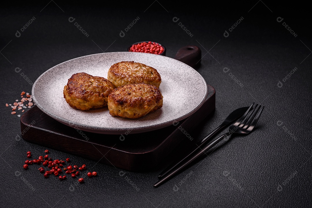 Deliciosas costeletas de peixe picado frito fresco com especiarias e ervas sobre um fundo escuro de concreto