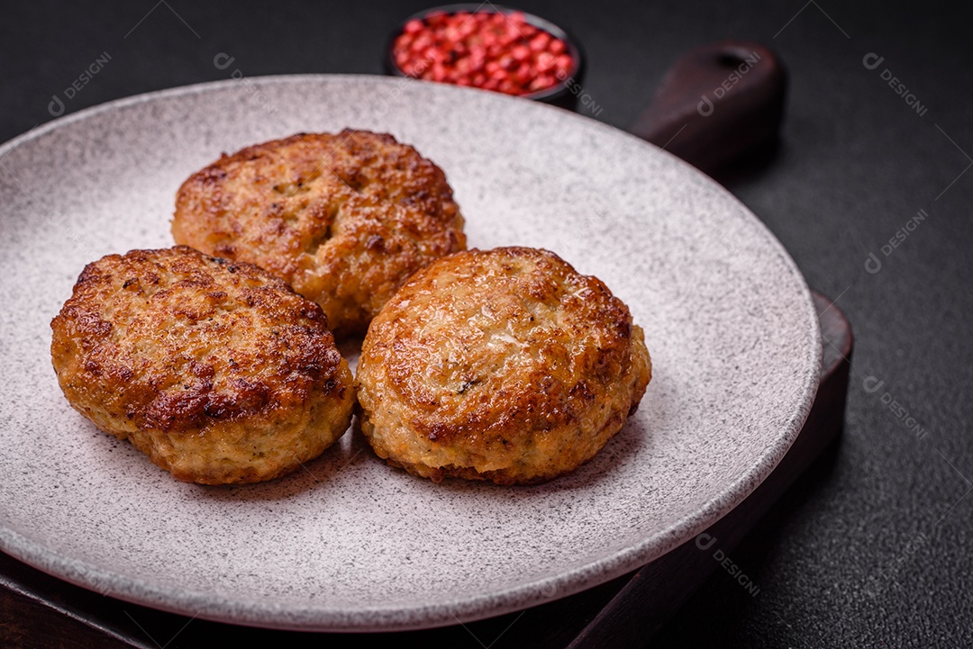 Deliciosas costeletas de peixe picado frito fresco com especiarias e ervas sobre um fundo escuro de concreto