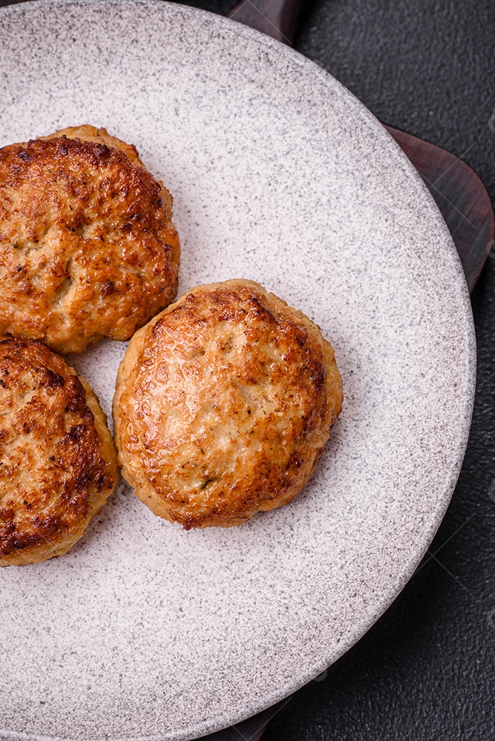Deliciosas costeletas de peixe picado frito fresco com especiarias e ervas sobre um fundo escuro de concreto