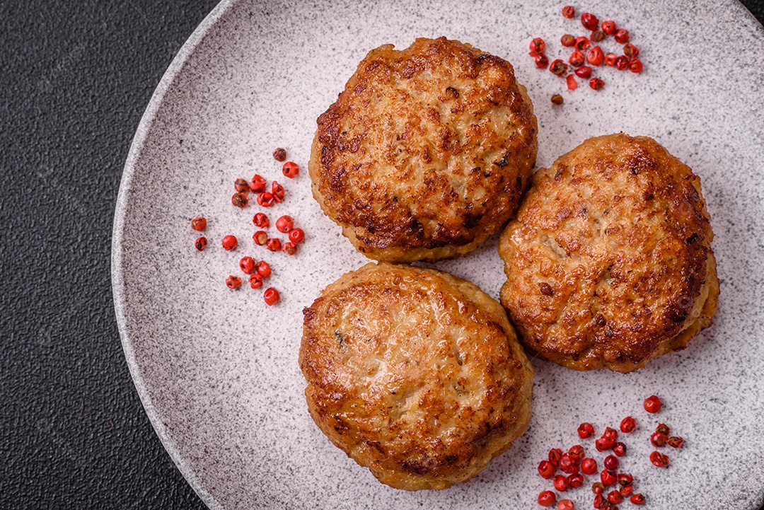 Deliciosas costeletas de peixe picado frito fresco com especiarias e ervas sobre um fundo escuro de concreto