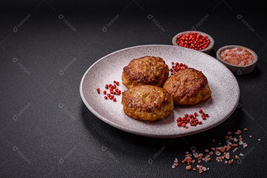 Deliciosas costeletas de peixe picado frito fresco com especiarias e ervas sobre um fundo escuro de concreto