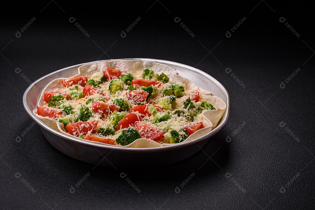 Deliciosa quiche com tomate, queijo, frango, especiarias e ervas sobre um fundo escuro de concreto