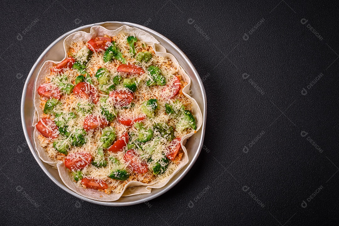 Deliciosa quiche com tomate, queijo, frango, especiarias e ervas sobre um fundo escuro de concreto