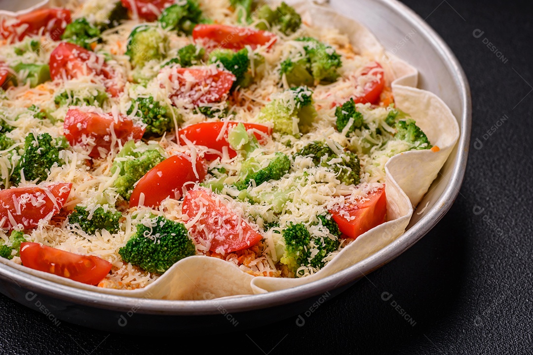 Deliciosa quiche com tomate, queijo, frango, especiarias e ervas sobre um fundo escuro de concreto