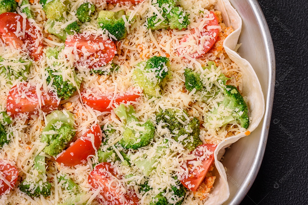 Deliciosa quiche com tomate, queijo, frango, especiarias e ervas sobre um fundo escuro de concreto