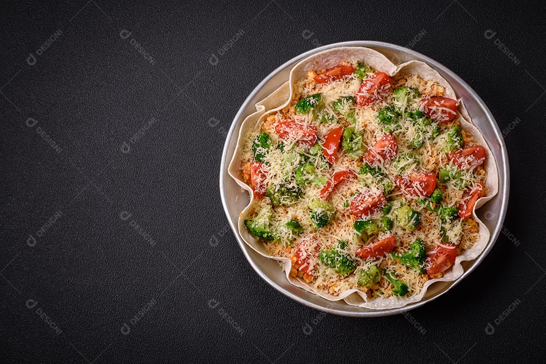 Deliciosa quiche com tomate, queijo, frango, especiarias e ervas sobre um fundo escuro de concreto