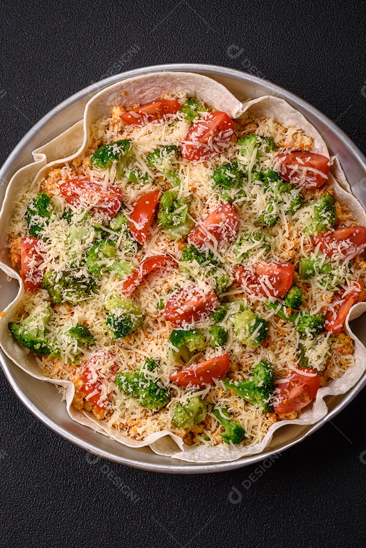 Deliciosa quiche com tomate, queijo, frango, especiarias e ervas sobre um fundo escuro de concreto