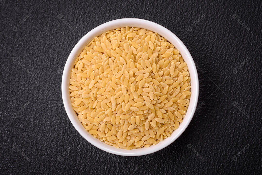 Grãos de mingau de trigo Ptitim em um fundo escuro de concreto. Preparando um café da manhã delicioso e nutritivo