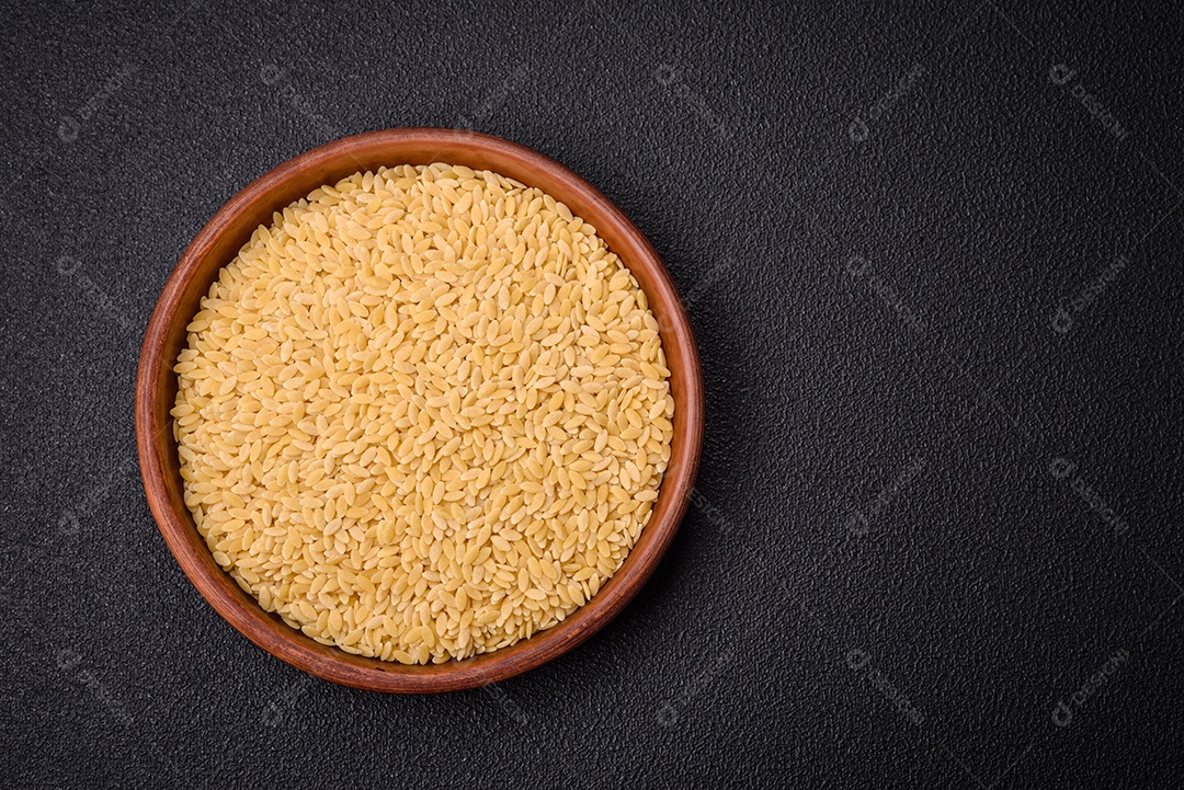 Grãos de mingau de trigo Ptitim em um fundo escuro de concreto. Preparando um café da manhã delicioso e nutritivo