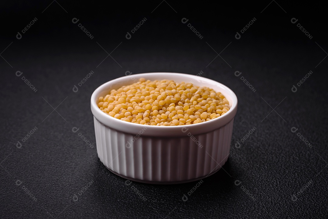 Grãos de mingau de trigo Ptitim em um fundo escuro de concreto. Preparando um café da manhã delicioso e nutritivo