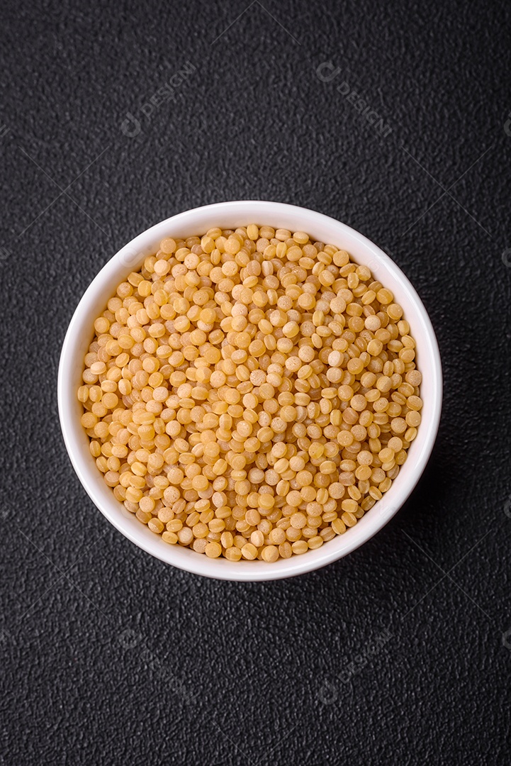 Grãos de mingau de trigo Ptitim em um fundo escuro de concreto. Preparando um café da manhã delicioso e nutritivo