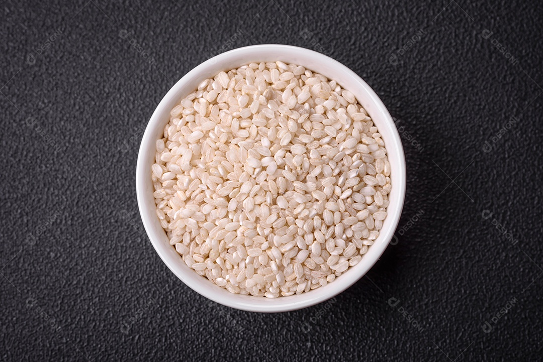 Grandes grãos de arroz branco cru em uma tigela de cerâmica. Cozinhando um delicioso mingau nutritivo