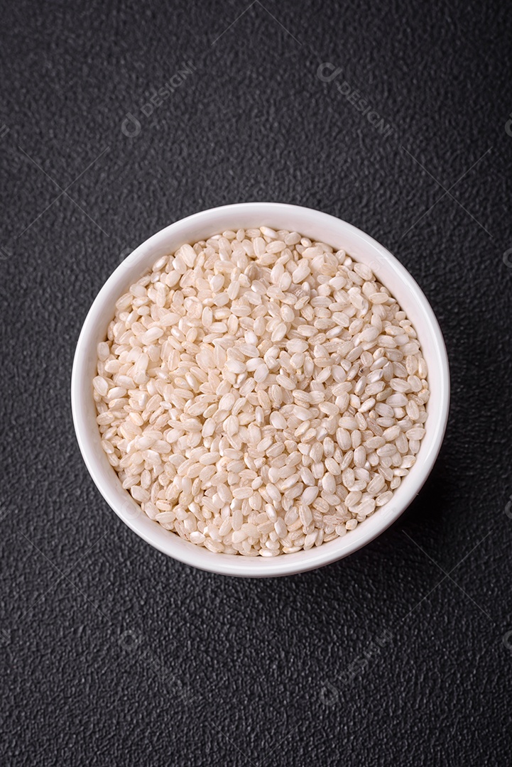 Grandes grãos de arroz branco cru em uma tigela de cerâmica. Cozinhando um delicioso mingau nutritivo