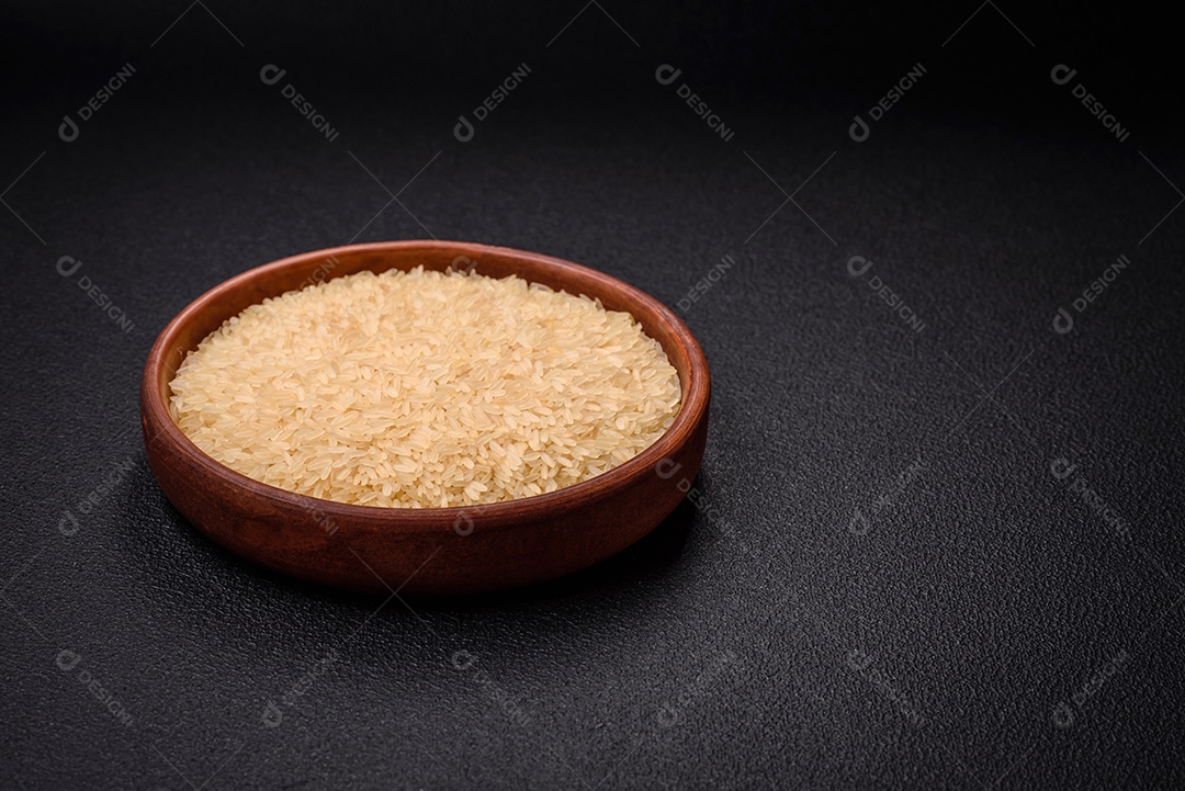 Grandes grãos de arroz branco cru em uma tigela de cerâmica. Cozinhando um delicioso mingau nutritivo