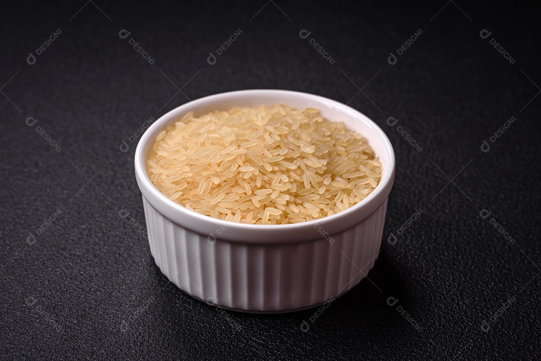 Grandes grãos de arroz branco cru em uma tigela de cerâmica. Cozinhando um delicioso mingau nutritivo