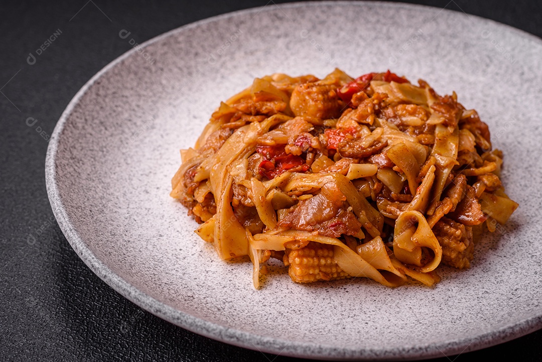 Delicioso prato de udon asiático com legumes, cogumelos, sal e especiarias numa placa cerâmica sobre um fundo escuro de concreto