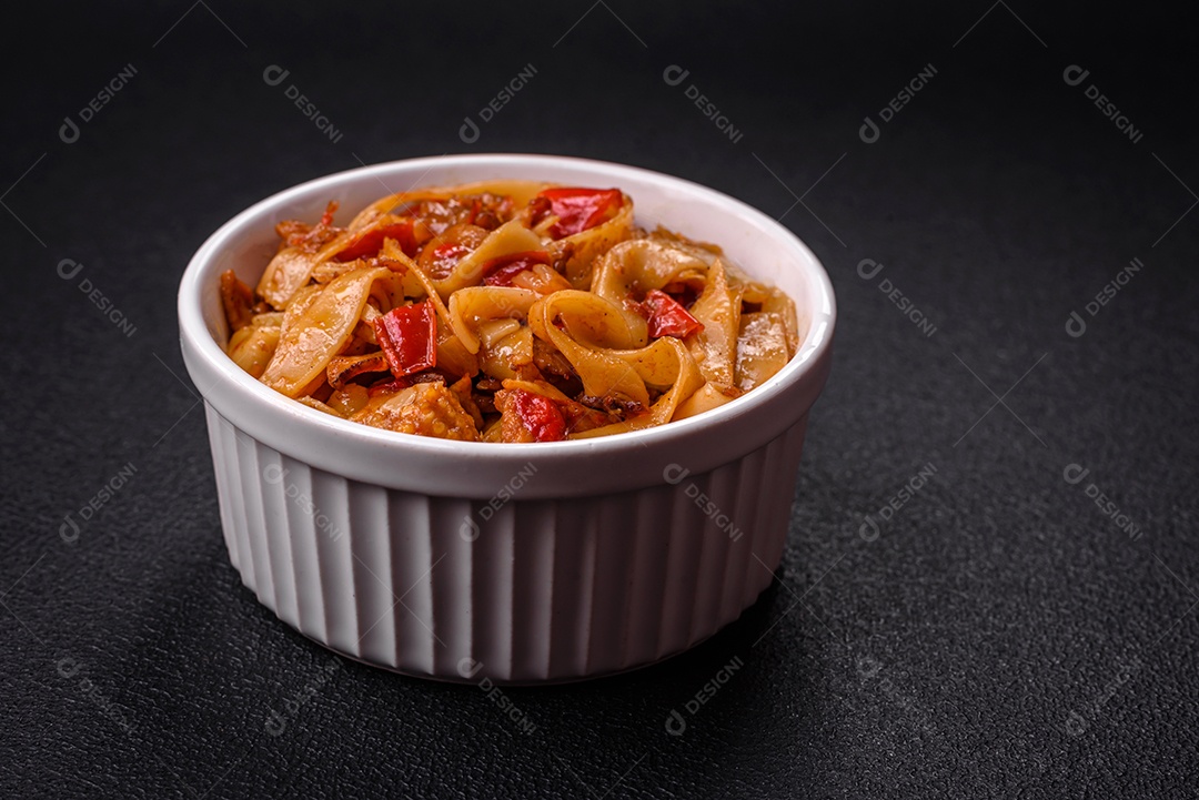 Delicioso prato de udon asiático com legumes, cogumelos, sal e especiarias numa placa cerâmica sobre um fundo escuro de concreto