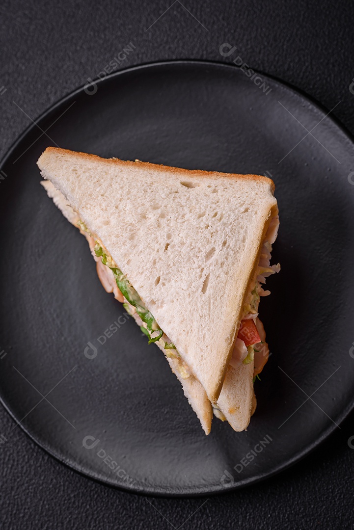 Delicioso sanduíche nutritivo com pão torrado, presunto, tomate, queijo e molho sobre um fundo escuro de concreto