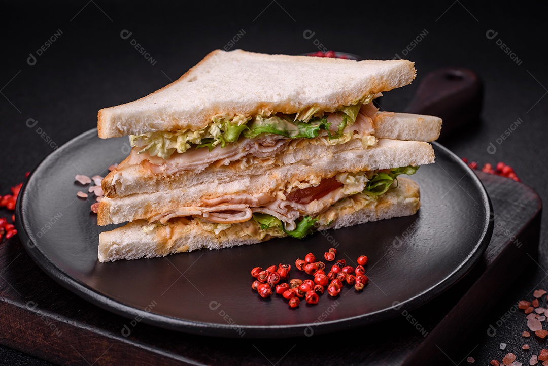 Delicioso sanduíche nutritivo com pão torrado, presunto, tomate, queijo e molho sobre um fundo escuro de concreto