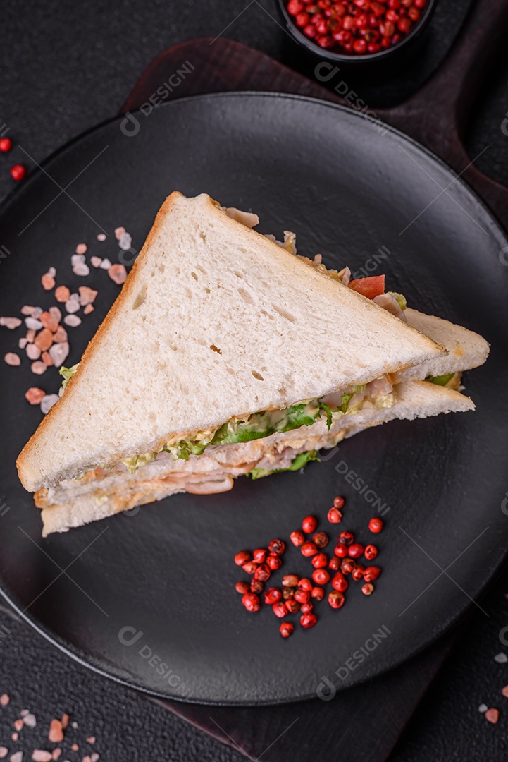 Delicioso sanduíche nutritivo com pão torrado, presunto, tomate, queijo e molho sobre um fundo escuro de concreto