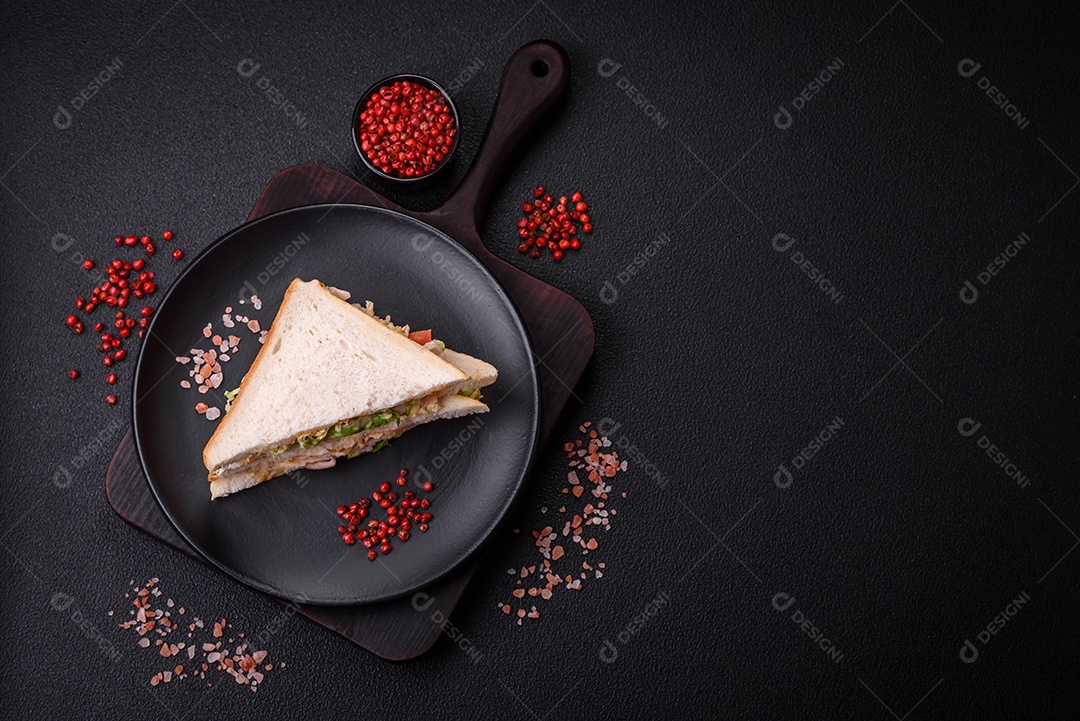 Delicioso sanduíche nutritivo com pão torrado, presunto, tomate, queijo e molho sobre um fundo escuro de concreto