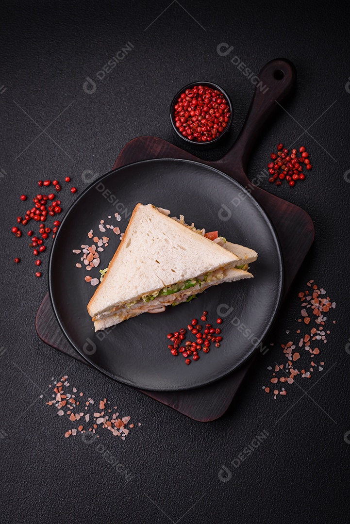 Delicioso sanduíche nutritivo com pão torrado, presunto, tomate, queijo e molho sobre um fundo escuro de concreto
