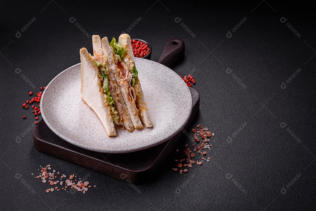 Delicioso sanduíche nutritivo com pão torrado, presunto, tomate, queijo e molho sobre um fundo escuro de concreto