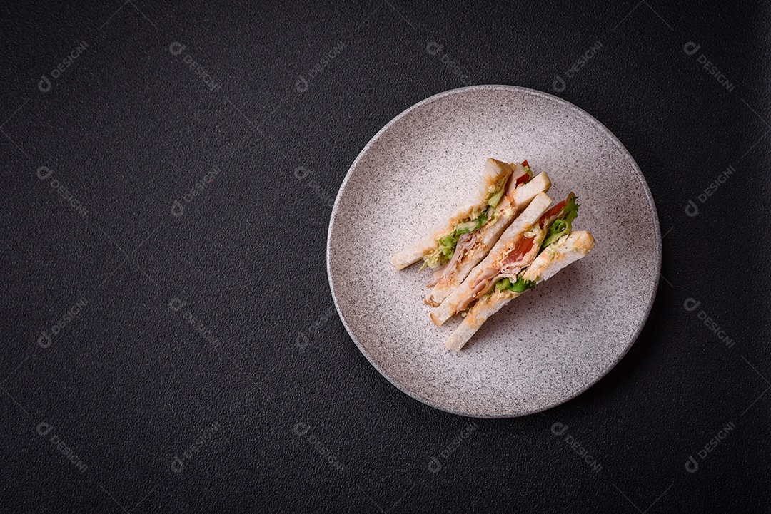 Delicioso sanduíche nutritivo com pão torrado, presunto, tomate, queijo e molho sobre um fundo escuro de concreto
