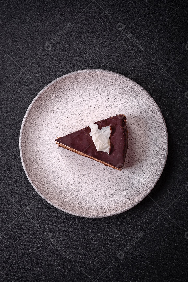 Pedaço de delicioso bolo de chocolate doce com pão de ló e creme sobre um fundo escuro de concret