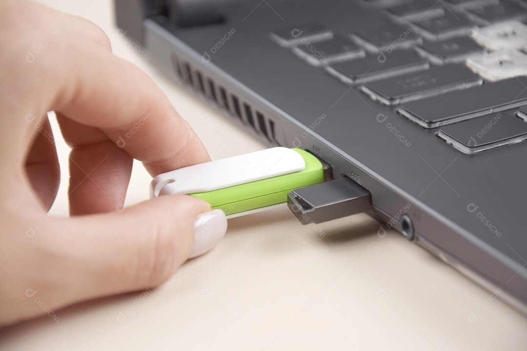 Mão colocando cartão de memória USB branco verde em um laptop aberto