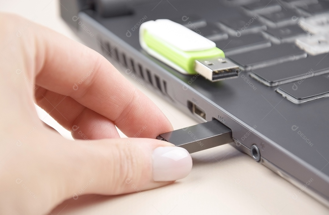 Colocando cartão de memória USB branco verde e preto no teclado de um laptop aberto