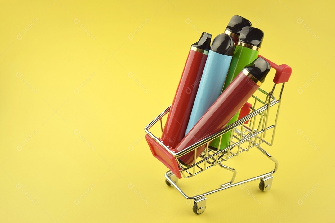 Carrinho de compra com cigarros eletrônicos dentro sobre fundo amarelo