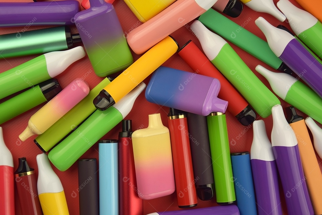 Muitos cigarros eletrônicos descartáveis ​​multicoloridos em fundo vermelho