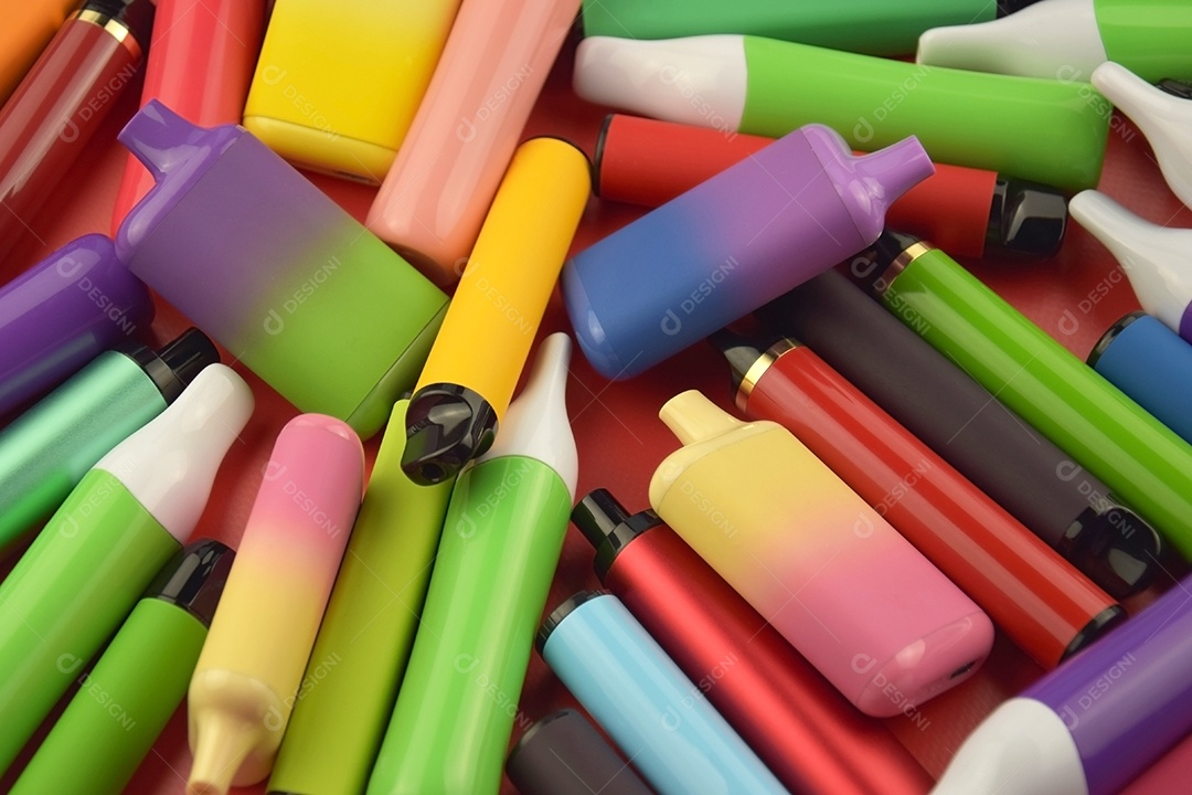 Muitos cigarros eletrônicos descartáveis ​​multicoloridos em fundo vermelho