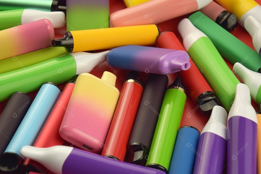 Muitos cigarros eletrônicos descartáveis ​​multicoloridos em fundo vermelho