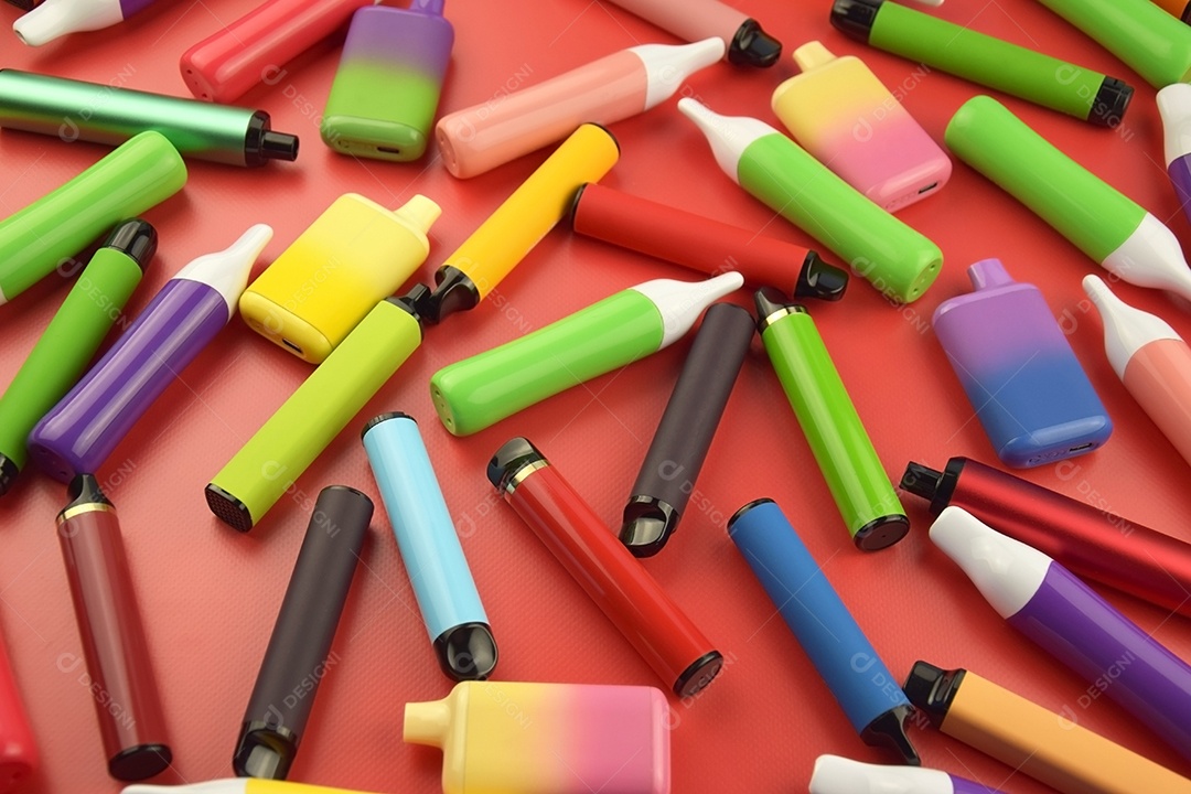 Muitos cigarros eletrônicos descartáveis ​​multicoloridos em fundo vermelho
