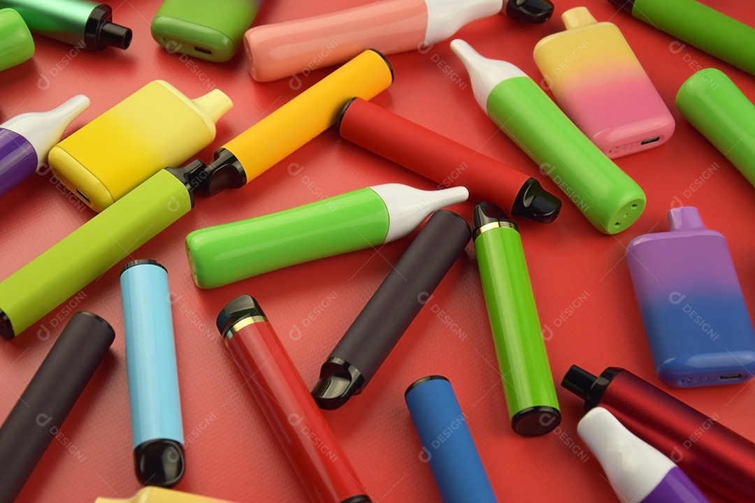 Muitos cigarros eletrônicos descartáveis ​​multicoloridos em fundo vermelho