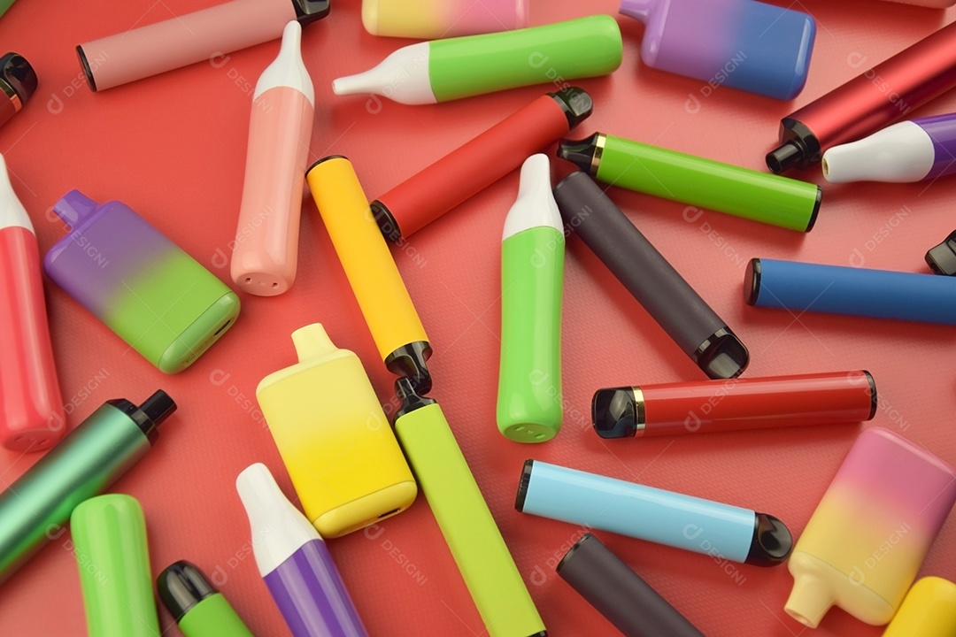 Muitos cigarros eletrônicos descartáveis ​​multicoloridos em fundo vermelho