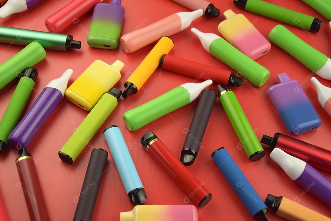 Vários cigarros eletrônicos descartáveis ​​multicoloridos sobre fundo vermelho