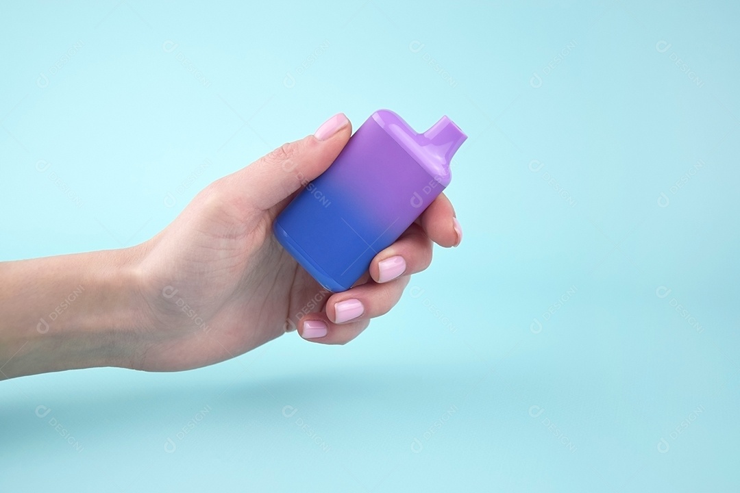 Mão segurando cigarro eletrônico sobre fundo azul