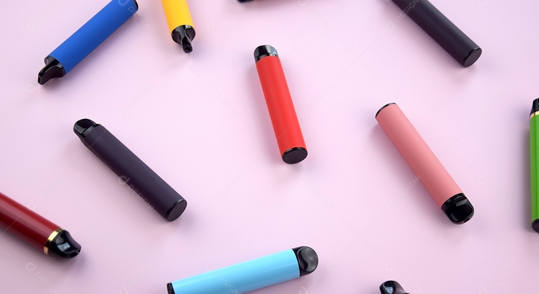 Vários cigarros eletrônicos descartáveis ​​multicoloridos em um fundo rosa