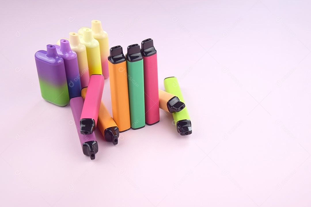 Vários cigarros eletrônicos descartáveis ​​multicoloridos em um fundo rosa