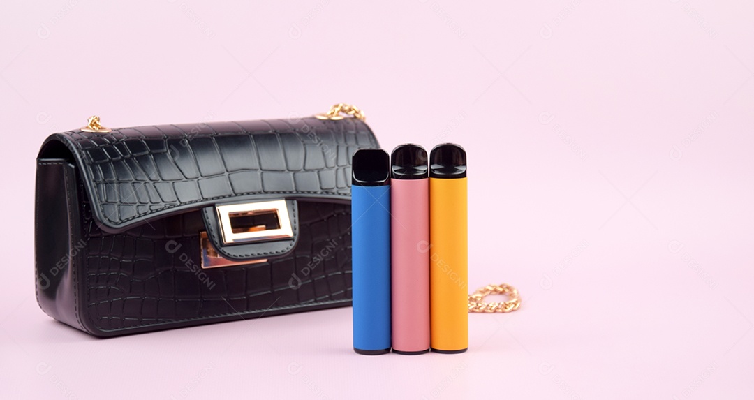 Bolsa preta e três cigarros eletrônicos colorido sobre fundo rosa claro